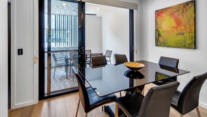 A modern dining area with a glass table, black chairs, and a bowl of fruit. - Modern, chic 3BR townhouse in luxury complex, top location, free wifi (Bulimba)