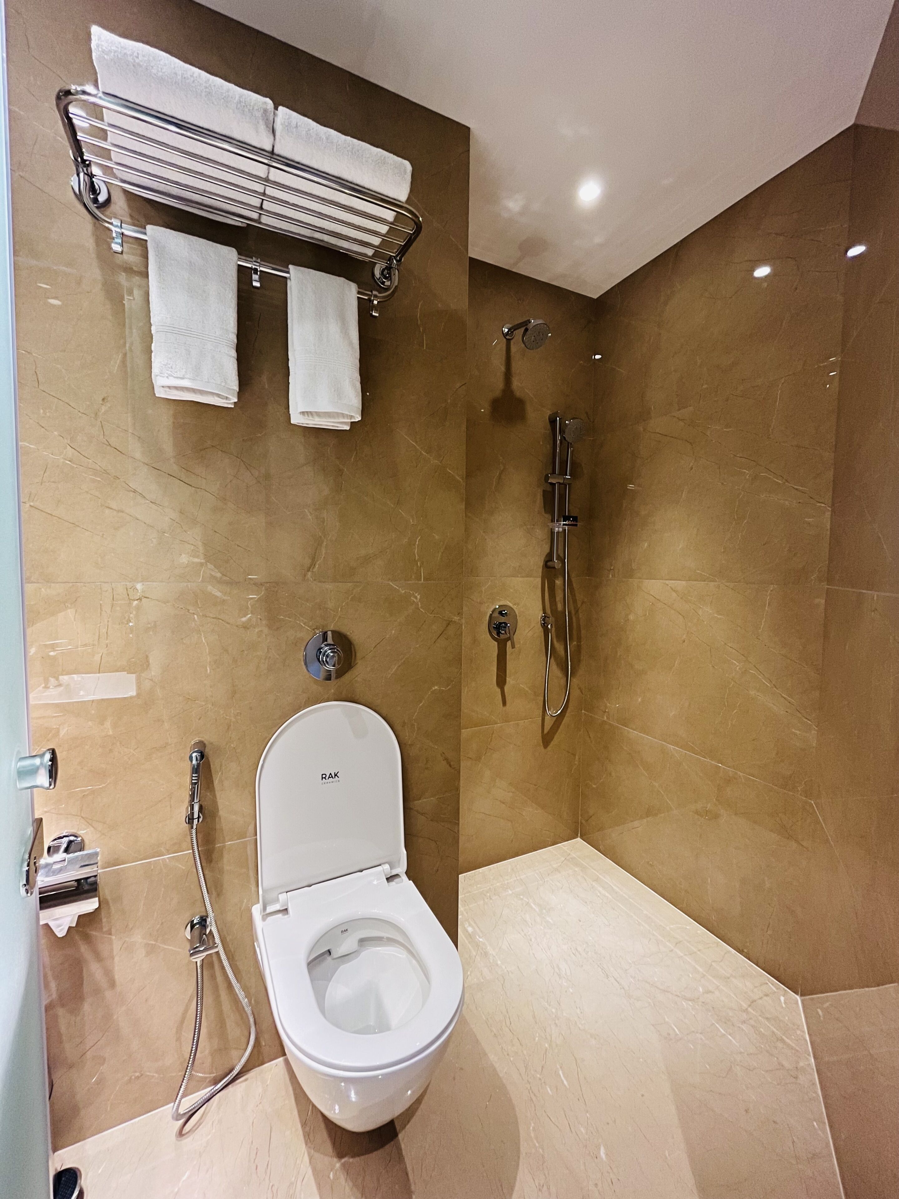Un baño moderno con inodoro, ducha y perchero para toallas.