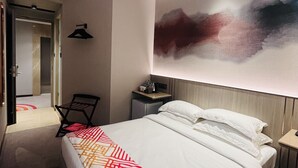 Ein modernes Hotelzimmer mit einem großen Bett, einem Nachttisch, einem Schreibtisch und einem Stuhl.