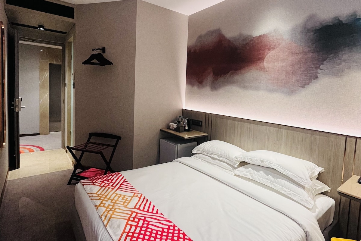Une chambre d’hôtel moderne avec un grand lit, une table de chevet, un bureau et une chaise.