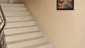 Una escala amb barana, parets beix i un quadre amb marc.