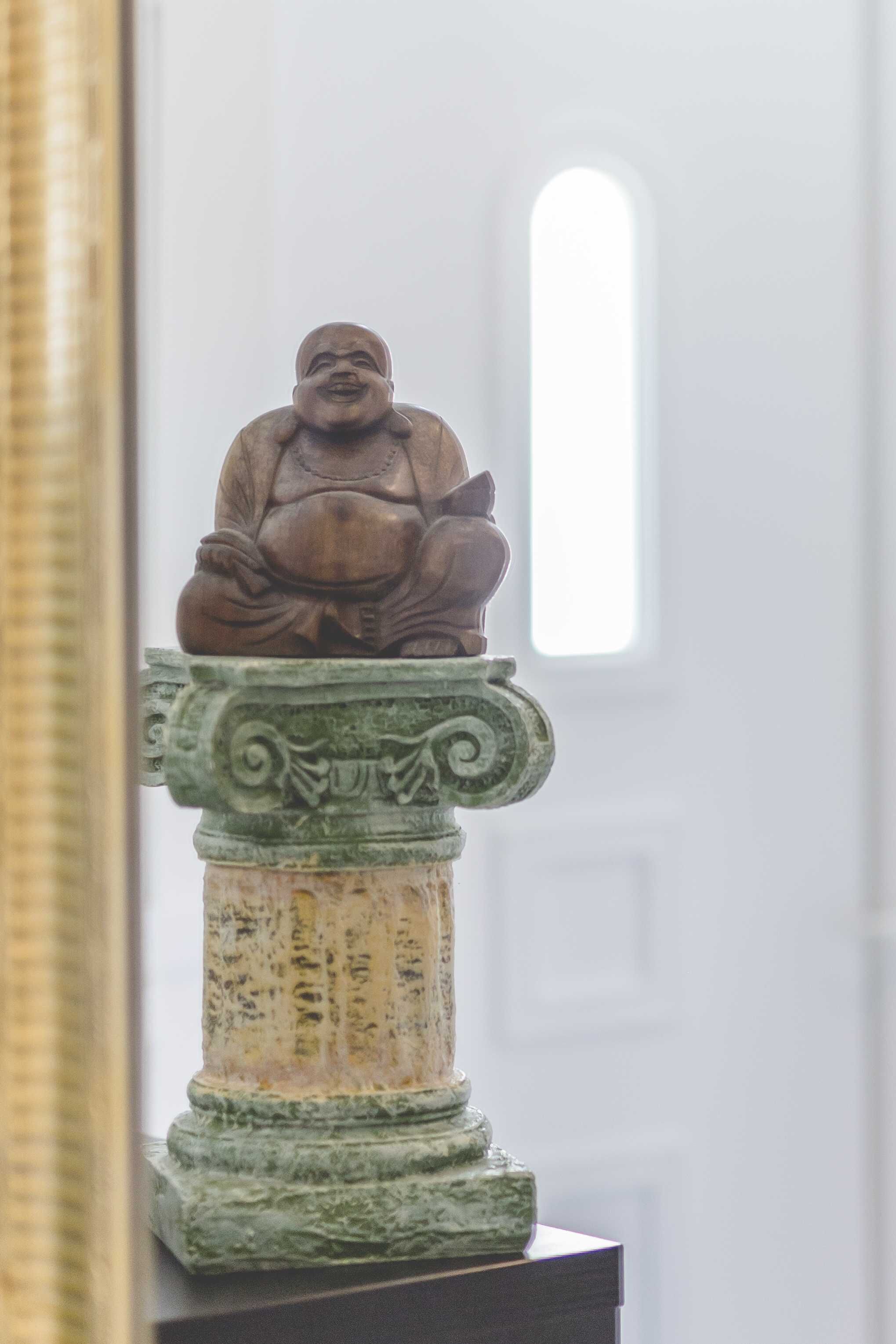 Une statue représentant une figure assise, placée sur un piédestal orné de sculptures complexes.