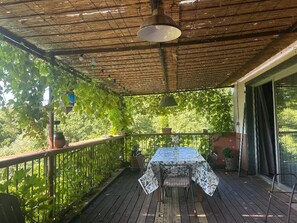 A covered patio with a table and chairs, surrounded by lush greenery. - Villa Bohème Pierre Blanche (Nîmes)