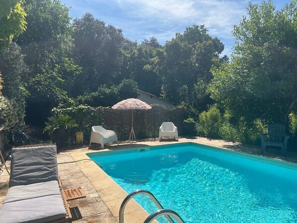 A swimming pool with lounge chairs and a small umbrella. - Villa Bohème Pierre Blanche (Nîmes)