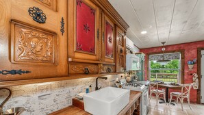 A kitchen with wooden cabinets, a white sink, and a dining area with white chairs. - Wilderness Country Inn: Italy (Mentone)