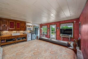 A spacious room with a large bed, a wooden cabinet, a kitchenette, and a television. - Wilderness Country Inn: Italy (Mentone)