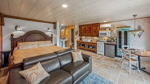 A bedroom with a large bed, a leather sofa, and a dining area with a table and chairs. - Wilderness Country Inn: Italy (Mentone)