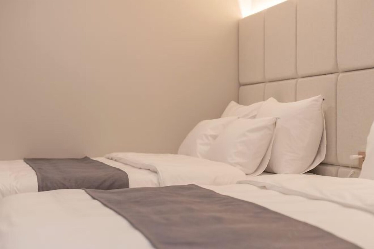 Una habitación de hotel con una cama, almohadas y cabecero.