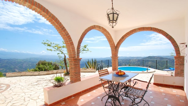 Une terrasse avec piscine, des sièges extérieurs et une vue sur les montagnes.