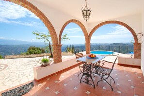 A terrace with a pool, outdoor seating, and a view of the mountains. - Villa Cuatro Vientos: Experience a Dream Holiday in the Heart of Andalusia (Comares)