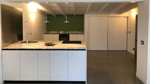 A modern kitchen with white cabinets, a marble countertop, and pendant lighting. - Apartment (Pietrasanta)