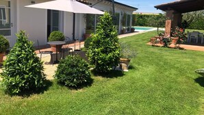 A well-maintained backyard with a patio, a swimming pool, and neatly trimmed bushes. - Apartment (Pietrasanta)