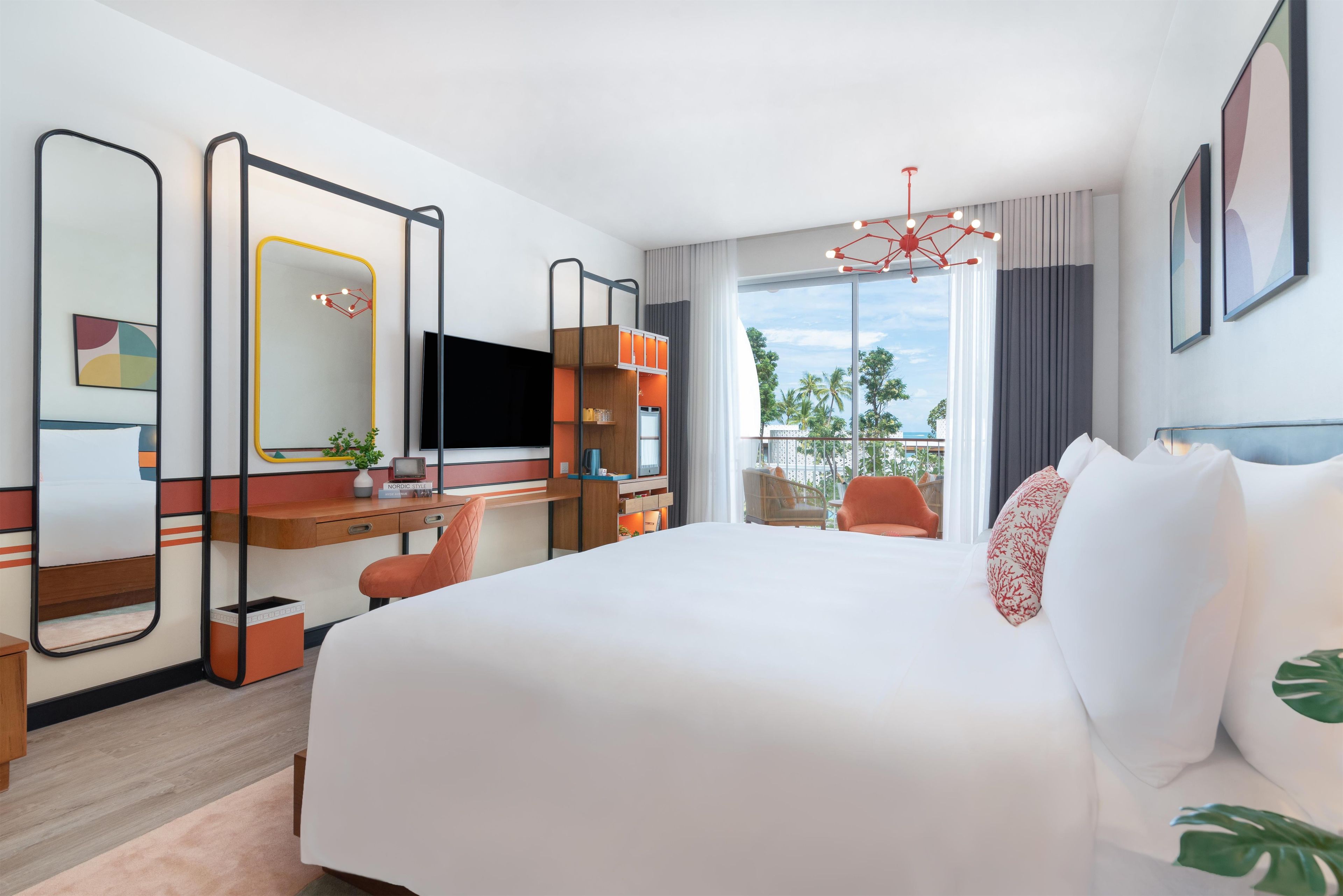 Habitación de hotel con una cama grande, un escritorio con computadora, un televisor y vistas al exterior.