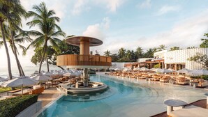 A pool area with lounge chairs, umbrellas, and palm trees. - Avani Chaweng Samui Hotel & Beach Club - Adults Only (Koh Samui)