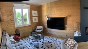 Un salon moderne avec une cheminée, un canapé et un téléviseur.