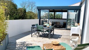 Une terrasse extérieure avec une table à manger, des chaises et un petit coin salon.