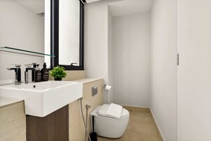A modern bathroom with a white sink, mirror, and toilet.