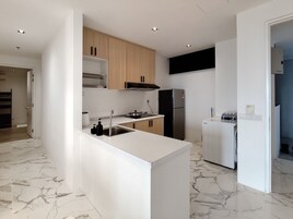 A modern kitchen with white countertops, a built-in oven, and a refrigerator.