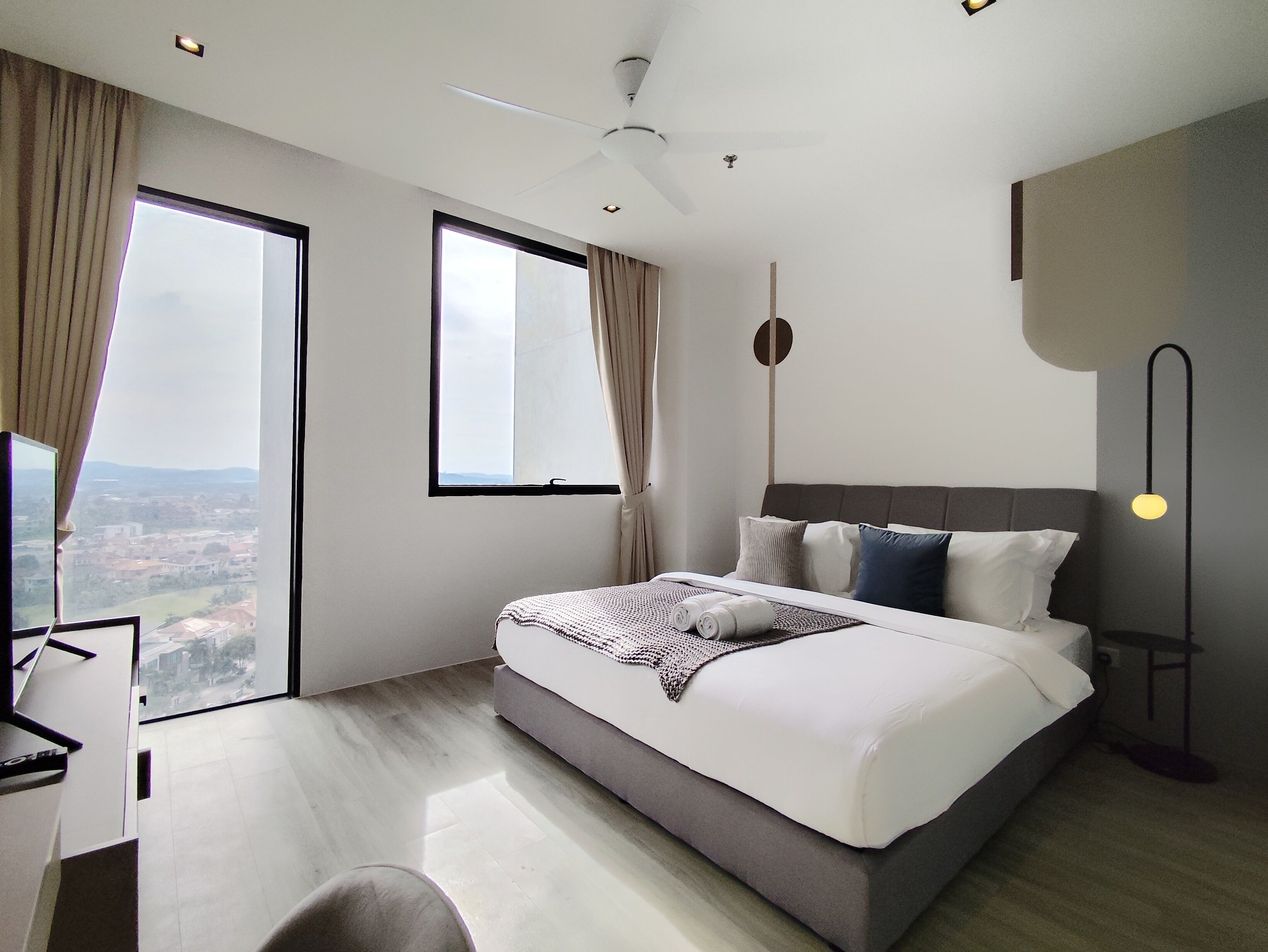 Una habitación de hotel moderna con una cama grande, un escritorio y vistas a la ciudad.