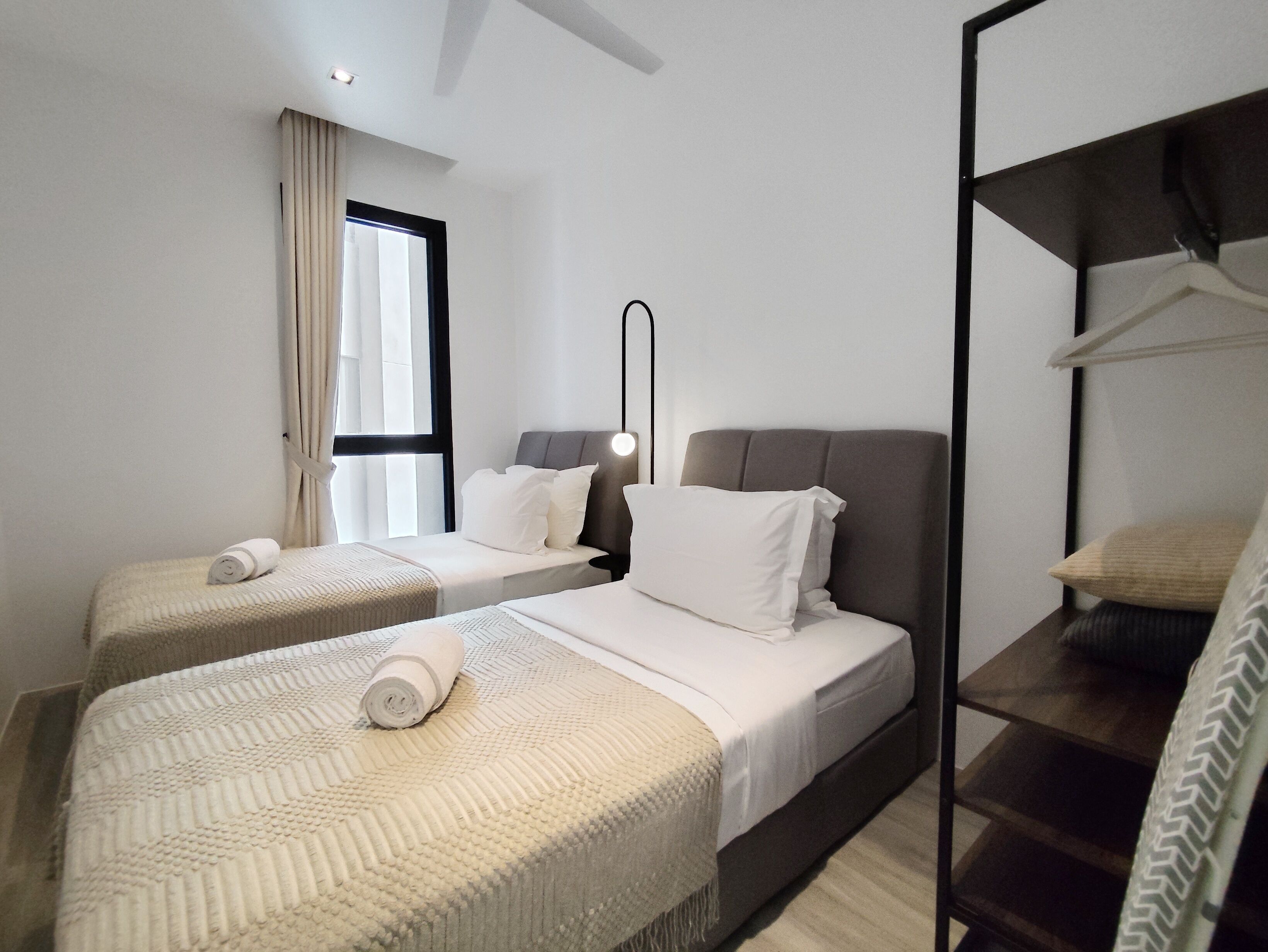 A hotel room with two beds, a wardrobe, a mirror, and a window with curtains.