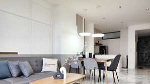 A modern living room with a grey sofa, a wooden coffee table, and a dining area with a wooden table and chairs. - Lumi Tropicana (Petaling Jaya)