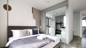 A modern bedroom with a large bed, a walk-in closet, and a glass shower area. - Lumi Tropicana (Petaling Jaya)