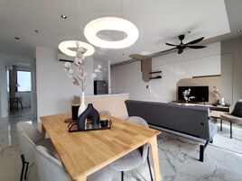 Una sala de estar moderna con una mesa de comedor de madera, un sofá gris y un televisor de pantalla plana.