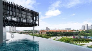 A rooftop infinity pool with a city view, a modern metal structure, and a landscaped area with greenery. - Lumi Tropicana (Petaling Jaya)
