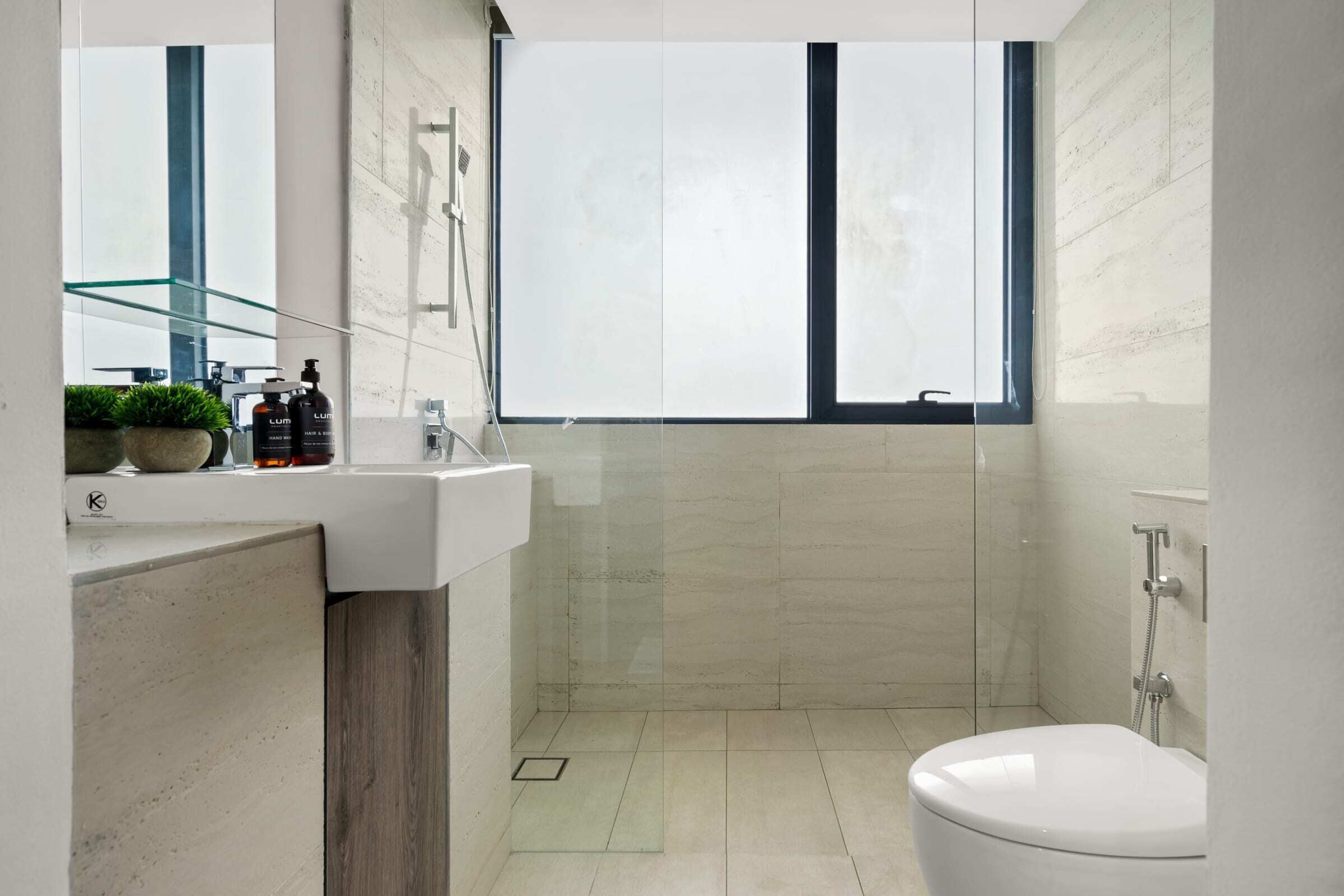 A modern bathroom with a glass shower enclosure, a white sink, and a toilet.