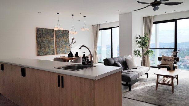 A modern living room with a grey sofa, a coffee table, and a view of the city through large windows. - Lumi Tropicana (Petaling Jaya)