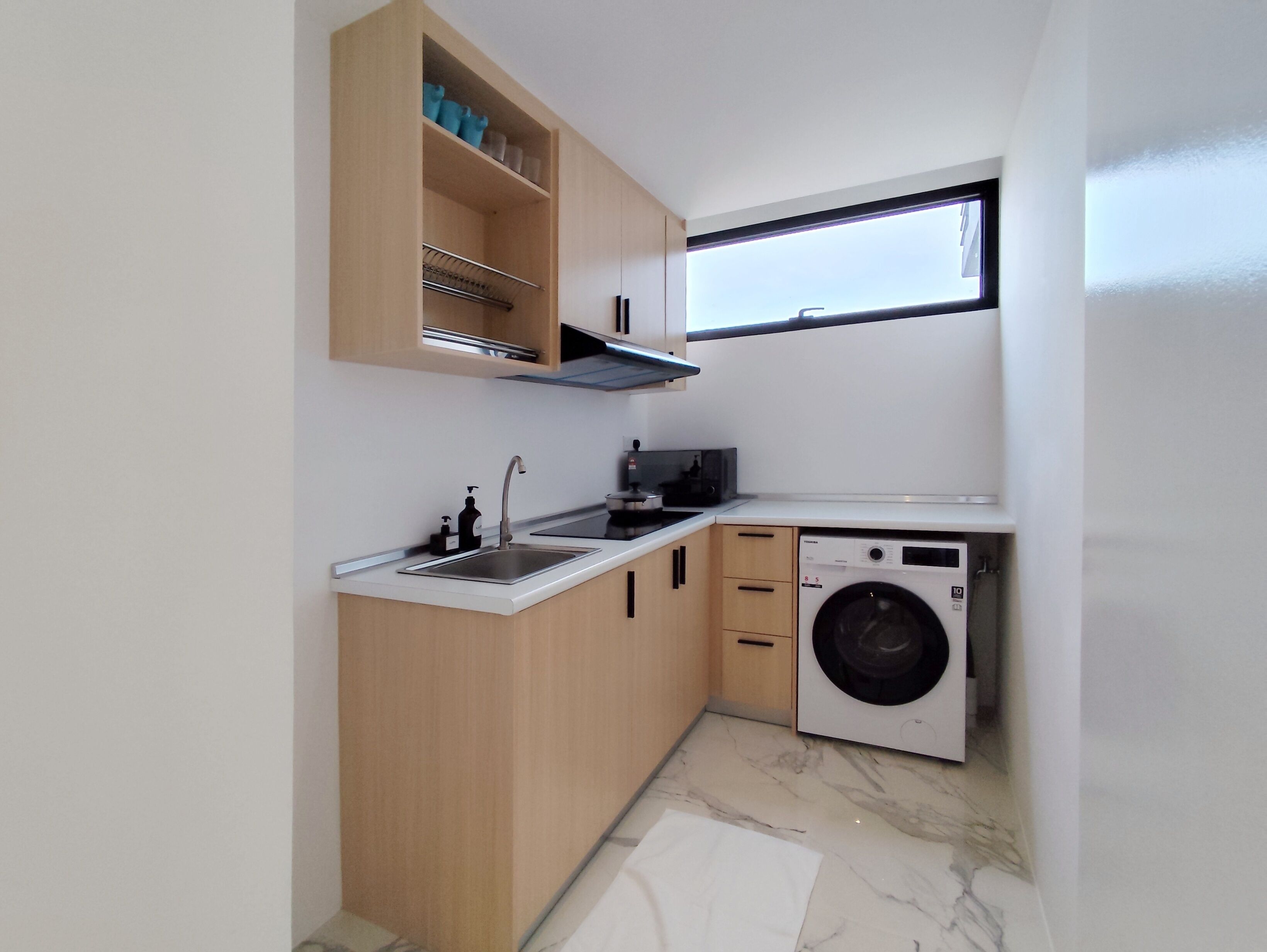 A compact kitchen with a built-in washing machine, a microwave, and a sink.