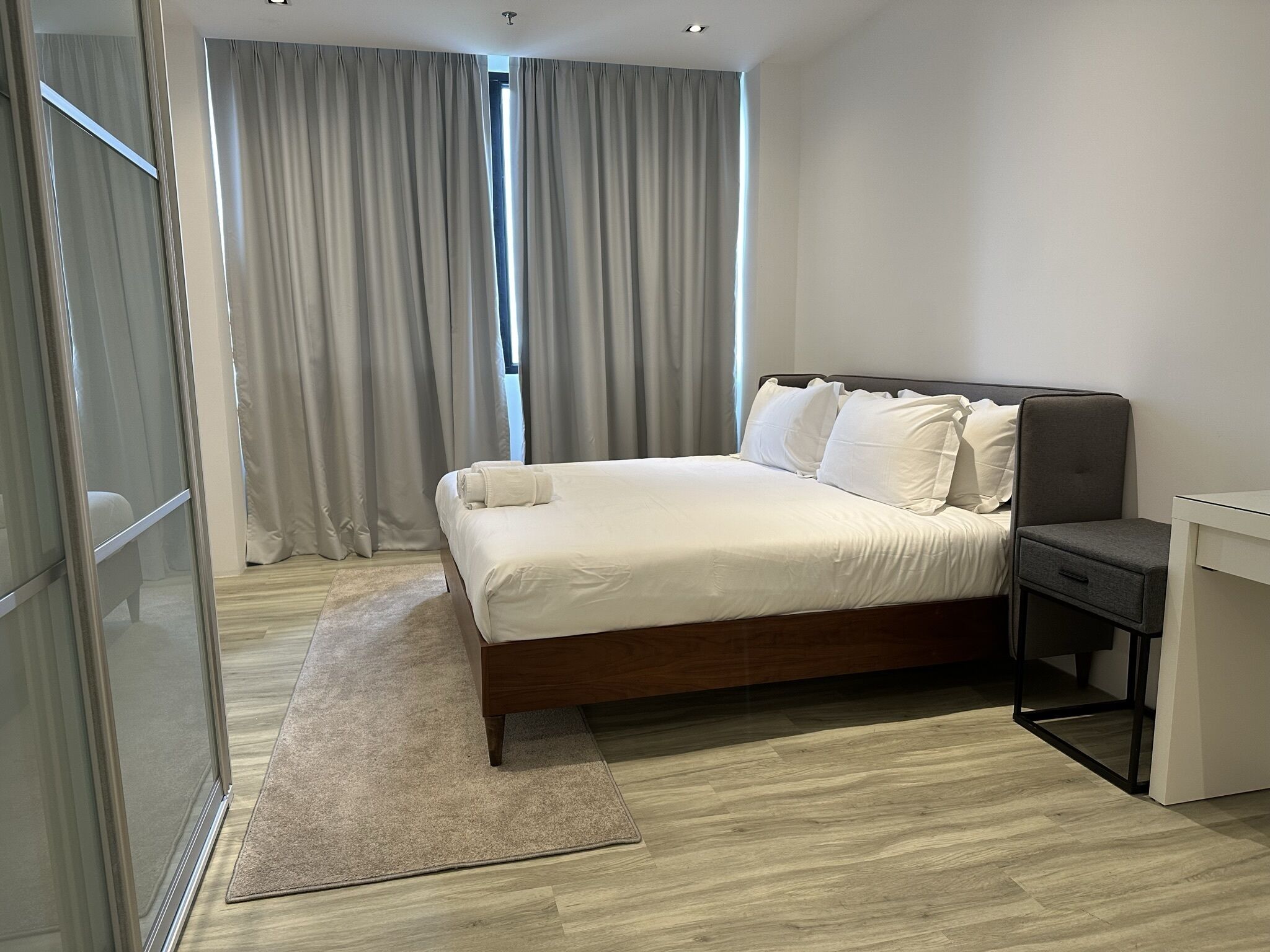 Ein modernes Hotelzimmer mit einem großen Bett, einem Nachttisch und einem Schreibtisch.