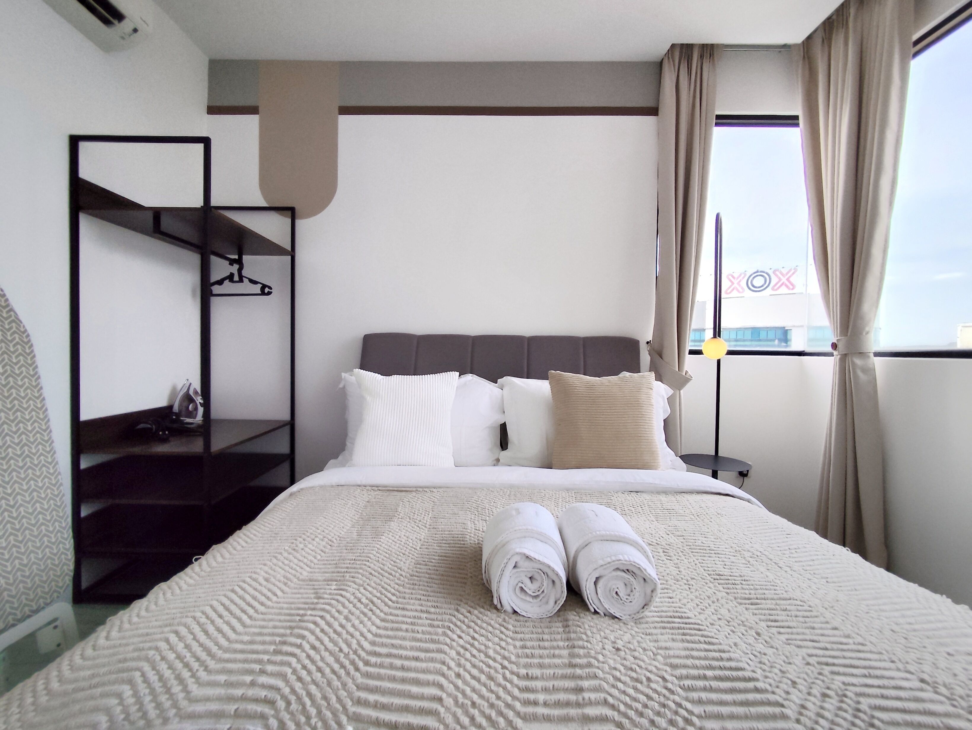 Une chambre d’hôtel avec un lit, une table de chevet, un miroir et une fenêtre avec des rideaux.