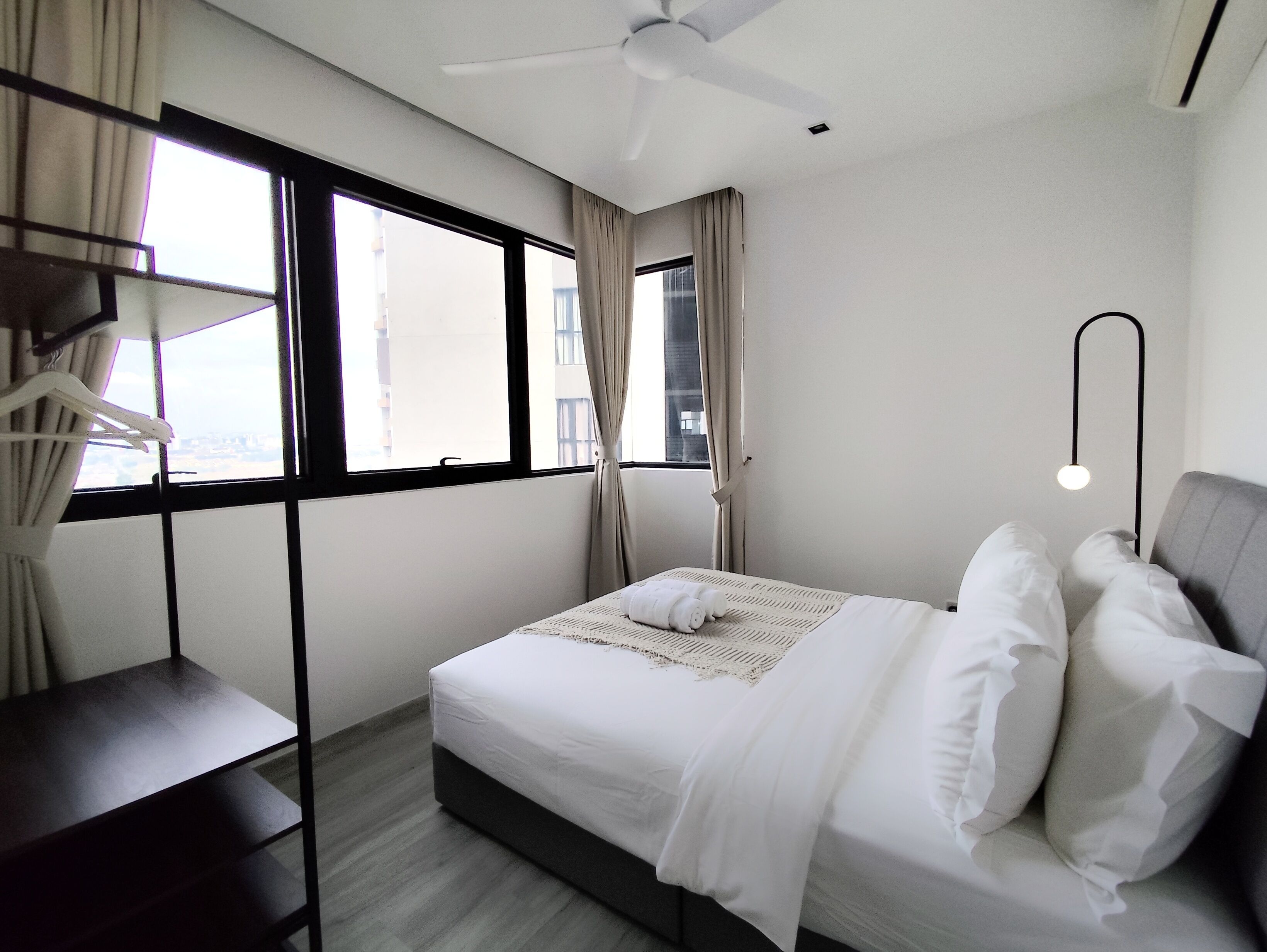 Habitació d'hotel moderna amb llit, escriptori i làmpada de peu.