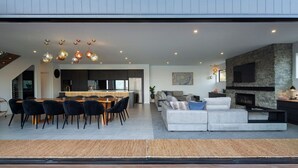 A modern living space with a dining area, sofa set, fireplace, and kitchen in the background.