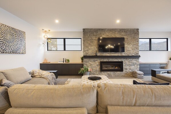 Una sala de estar moderna con chimenea de piedra, un televisor de pantalla plana grande y una zona de estar cómoda con sofás y una mesa de centro.