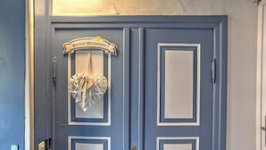 A blue door with a decorative heart hanging on it and a sign above that reads "Herzlich Willkommen". - fewo1846 - "Unsere Blume" / charming 2 room apartment with balcony / harbor view (Flensburg)