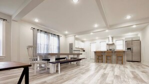 A spacious living area with a dining table, chairs, a kitchen area with a refrigerator, and a bench. - BRAND NEW LISTING - Northside Cottage (Hendersonville)