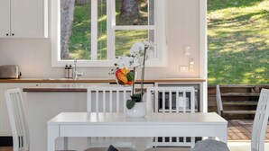 Cucina con finestra, pensili bianchi, piano di lavoro bianco e tavolo da pranzo con sedie.