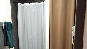 A bathroom with a wooden vanity, a white sink, a shower curtain, and a towel rack. - Apartment (NERAC)