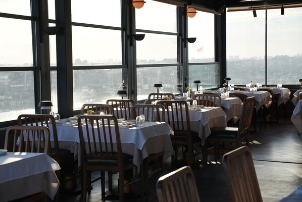 A restaurant with tables set for dining, large windows, and a view of the cityscape. - Ring Stone Hotels Bosphorus (Istanbul)