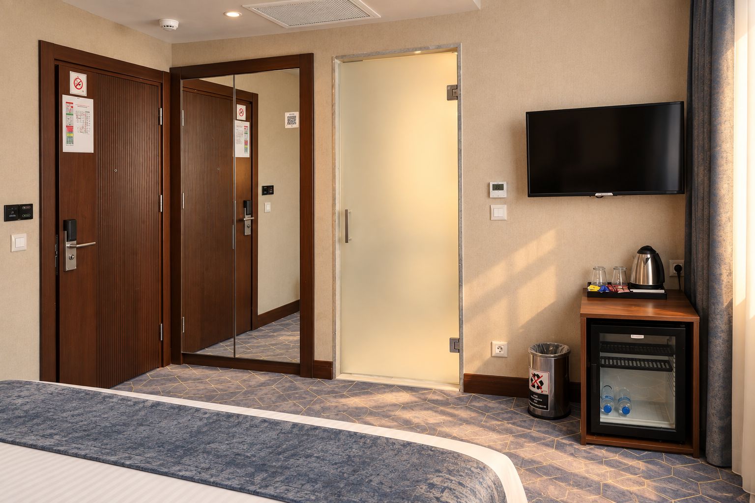 Una habitación de hotel con una cama, televisión, cafetera y cubo de basura.