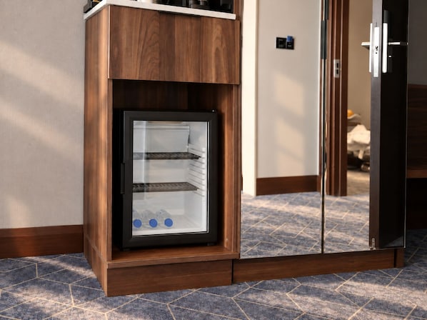 Une cuisine moderne dotée d’un réfrigérateur encastré, de meubles en bois et d’un sol carrelé.