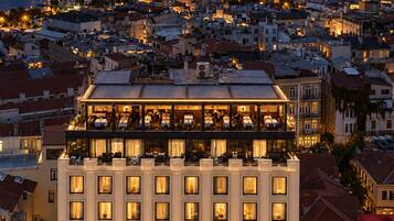 Un hôtel à étages, doté d’une cour intérieure et offrant une vue sur le paysage urbain illuminé la nuit.