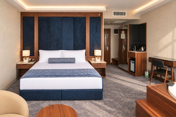 Une chambre d’hôtel avec un grand lit, des tables de chevet, un bureau et une chaise.