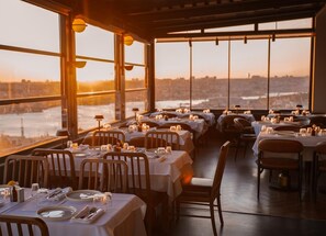 A restaurant with tables set for dining, large windows, and a view of a cityscape. - Ring Stone Hotels Bosphorus (Istanbul)