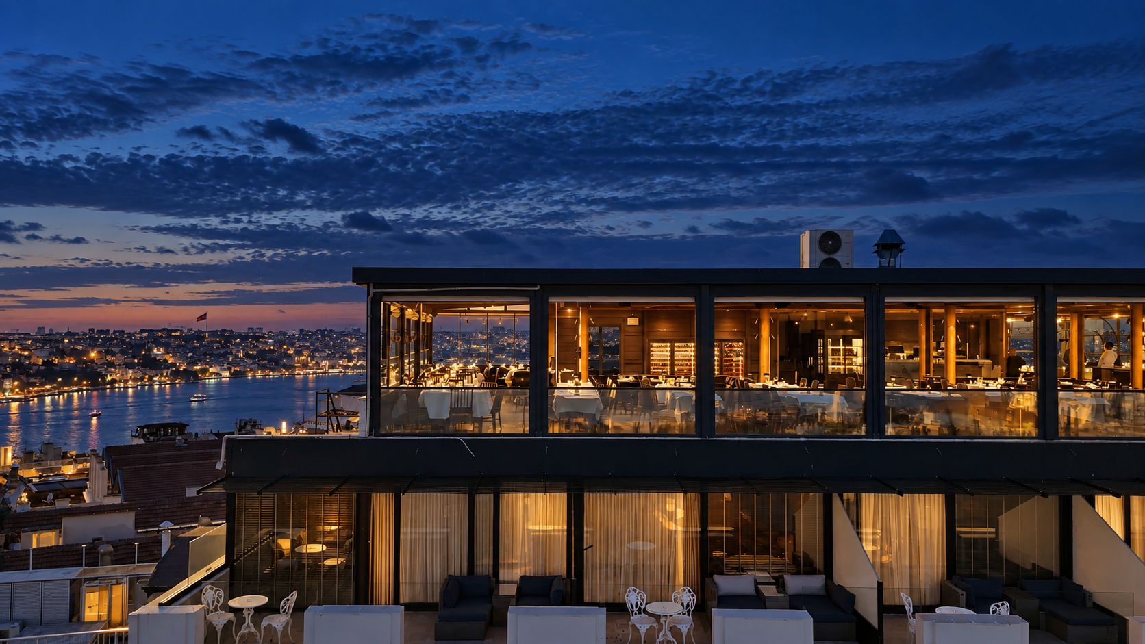 A modern building with a dining area overlooking a body of water.