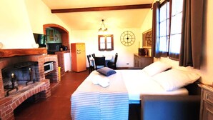 A cozy room with a bed, a fireplace, a dining area, and a kitchen. - Country house with pool sea view (camporosso)