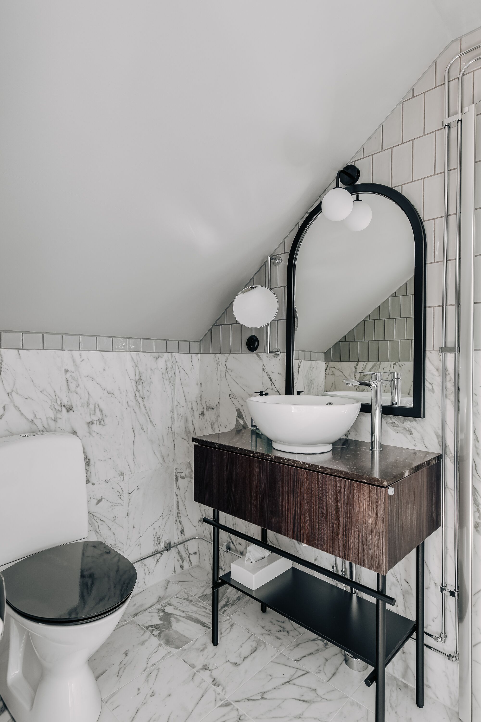 A bathroom with a white toilet, a white sink with a black countertop, and a mirror with a black frame.