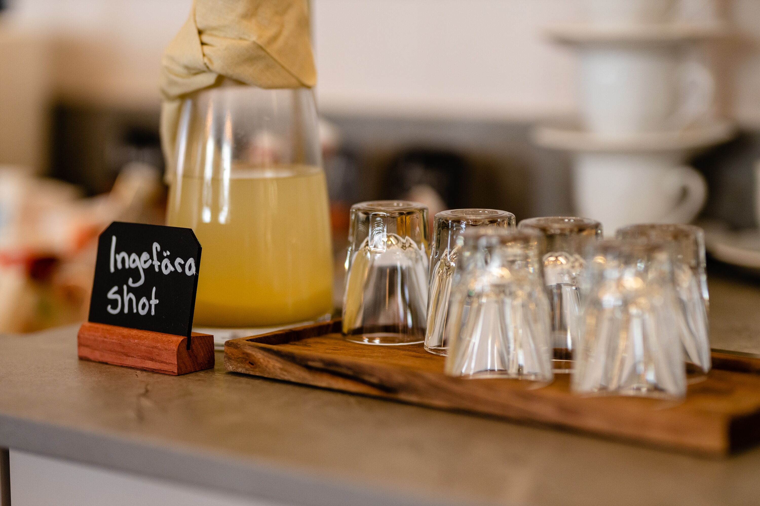 Un présentoir à boissons avec une pancarte indiquant « Inglera Shot » et plusieurs petits verres à shooter disposés sur un plateau en bois.